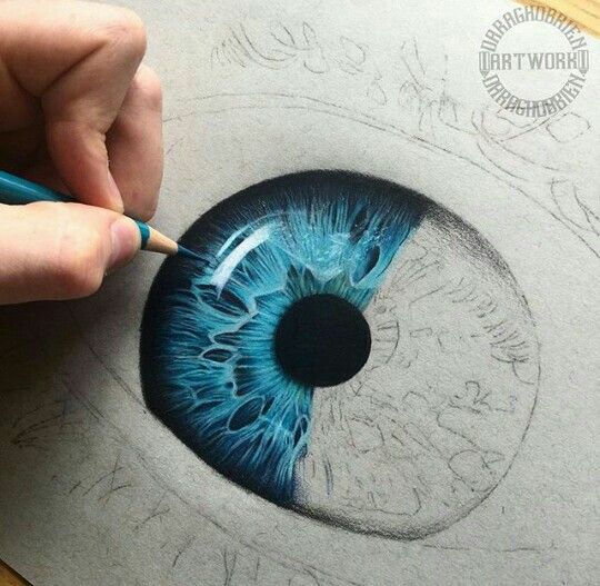 someone is drawing an eyeball with colored pencils on the paper and it looks like they have blue eyes