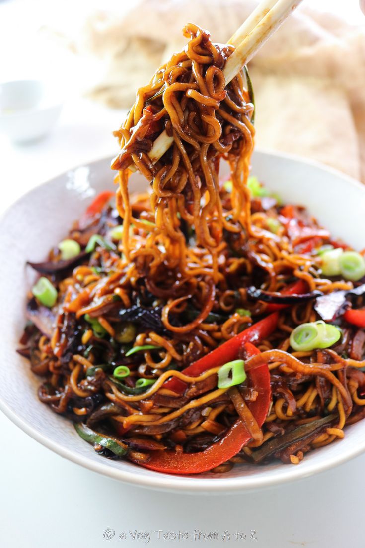 a bowl full of noodles and vegetables with chopsticks sticking out of the top