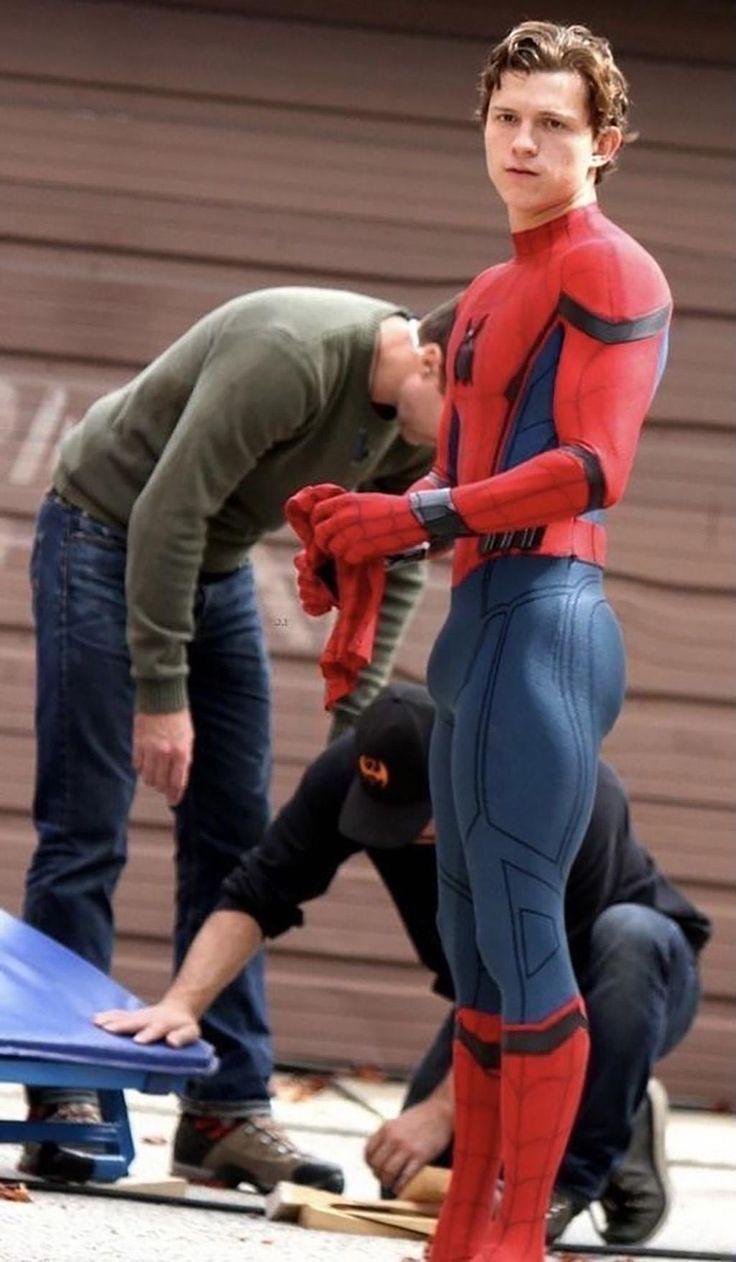 a man in a spider - man suit standing next to another man