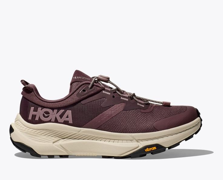 the hoka trekking shoe is shown in burgundy and beige colors, with white lettering on