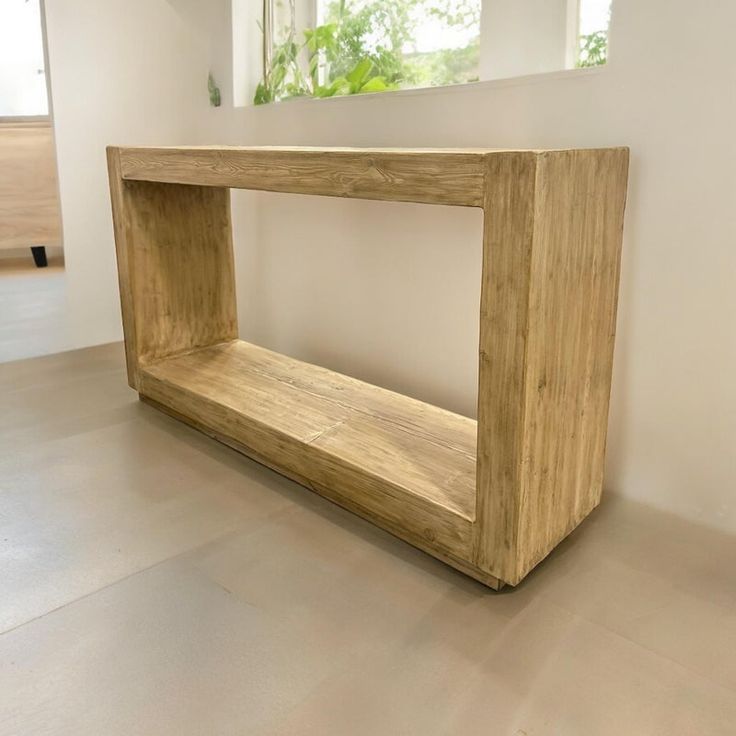 a wooden shelf sitting on top of a hard wood floor next to a white wall