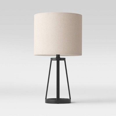 a table lamp with a white shade on it and a black stand next to it