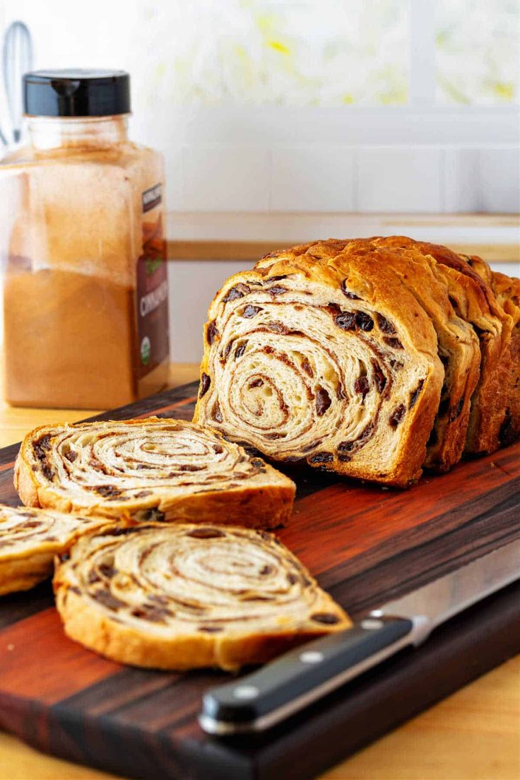 a loaf of cinnamon swirl bread sitting on top of a cutting board next to sliced bread