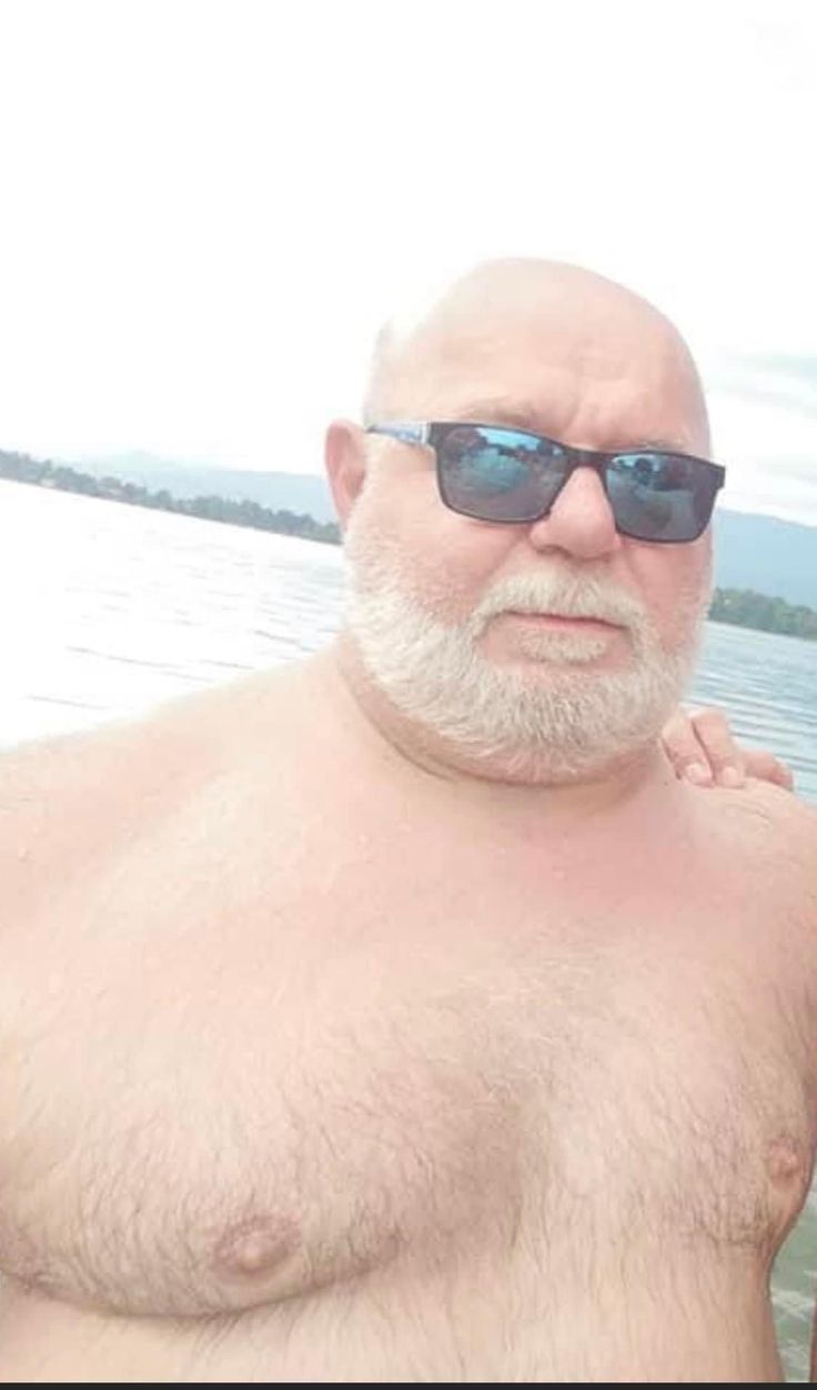 an older man with white hair and sunglasses standing next to a woman on a boat