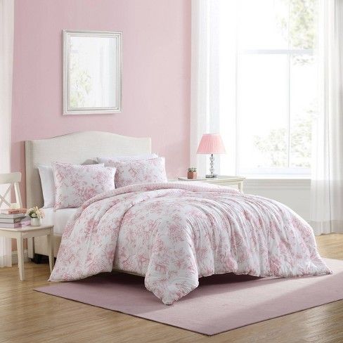 a bedroom with pink walls and bedding in the center, along with a rug on the floor