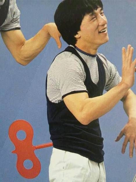 a young man holding a tennis racquet on top of a blue wall next to a pair of scissors