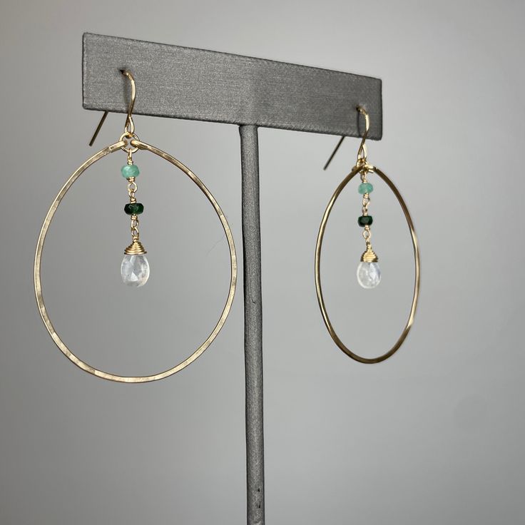 Details: This set includes a matching ruby and rainbow moonstone set. Hoops ~Hand hammered hoops.~Gold filled.~Ombre rubies or emeralds.~Rainbow moonstone focal stone.~Hoops measure approximately 1 1/2" in diameter.~Earrings measure approximately 2 1/4” from the top of the hook to the bottom of the bottom hoop. Necklace ~Gold filled.~Ombre rubies or emerald.~Rainbow moonstone focal stone.~9mm lobster clasp.~Measures 20".~1” extension that allows you to adjust the length of the necklace.~Little gem embellishment stone on the end of the extension chain. Emerald Jewelry With Natural Stones For Anniversary, Anniversary Jewelry With Natural Emerald Stones, Modern Round Faceted Jewelry, Modern Faceted Round Jewelry, Anniversary Emerald Jewelry With Natural Stones, Elegant Hoop Jewelry With Gemstone Accents, Modern Green Jewelry With Gemstone Accents, Modern Dangle Jewelry With Gemstone Accents, Gold Hoop Jewelry With Gemstone Accents