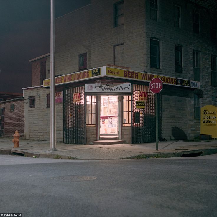 an empty street corner at night with a storefront and fire hydrant in the foreground