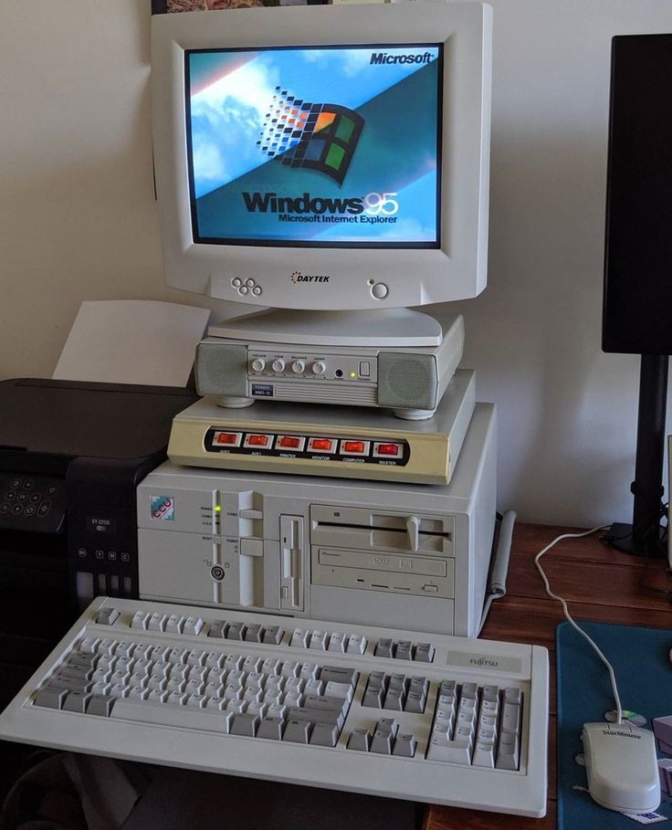 an old computer sitting on top of a desk next to a keyboard and monitor with windows logo