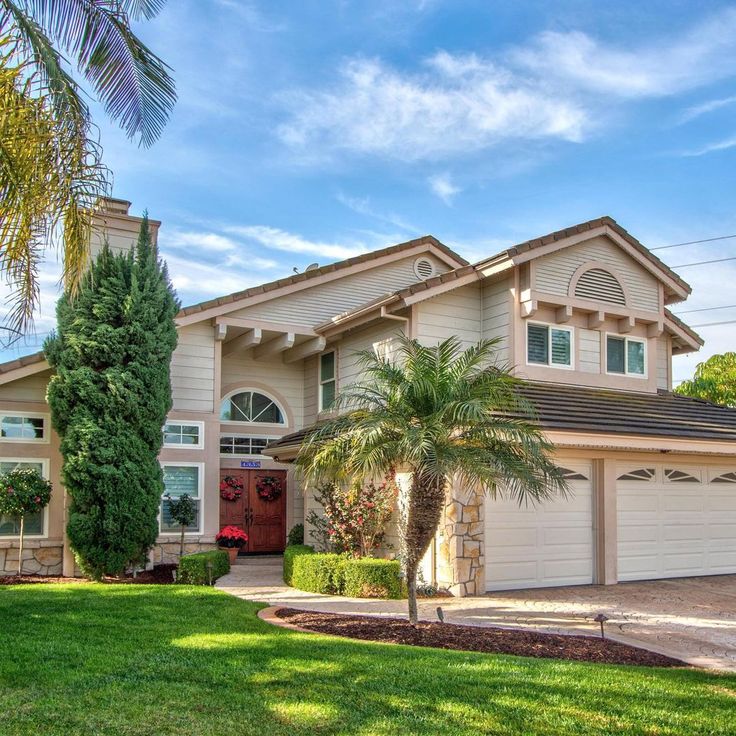 a large house with palm trees in front of it and a red door on the side