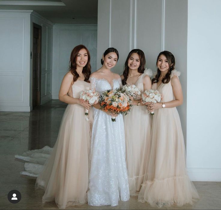 four bridesmaids pose for a photo in their wedding gowns