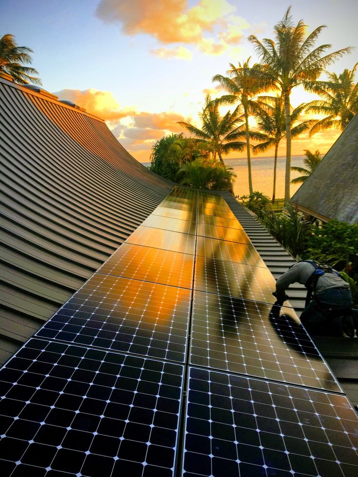 solar panels on the roof of a house with palm trees in the background at sunset