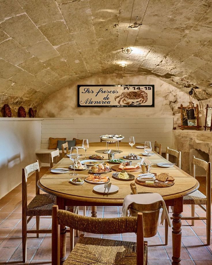 a dining table with plates and glasses on it in an old stone walled kitchen area