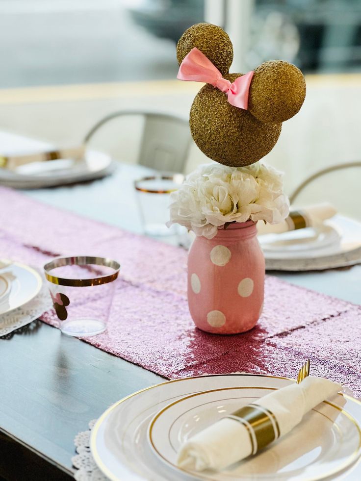 a minnie mouse centerpiece sitting on top of a pink vase filled with white flowers