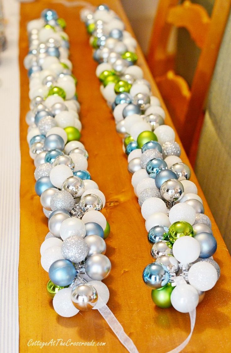 a long table with ornaments on it and some white, green and blue balls in the middle