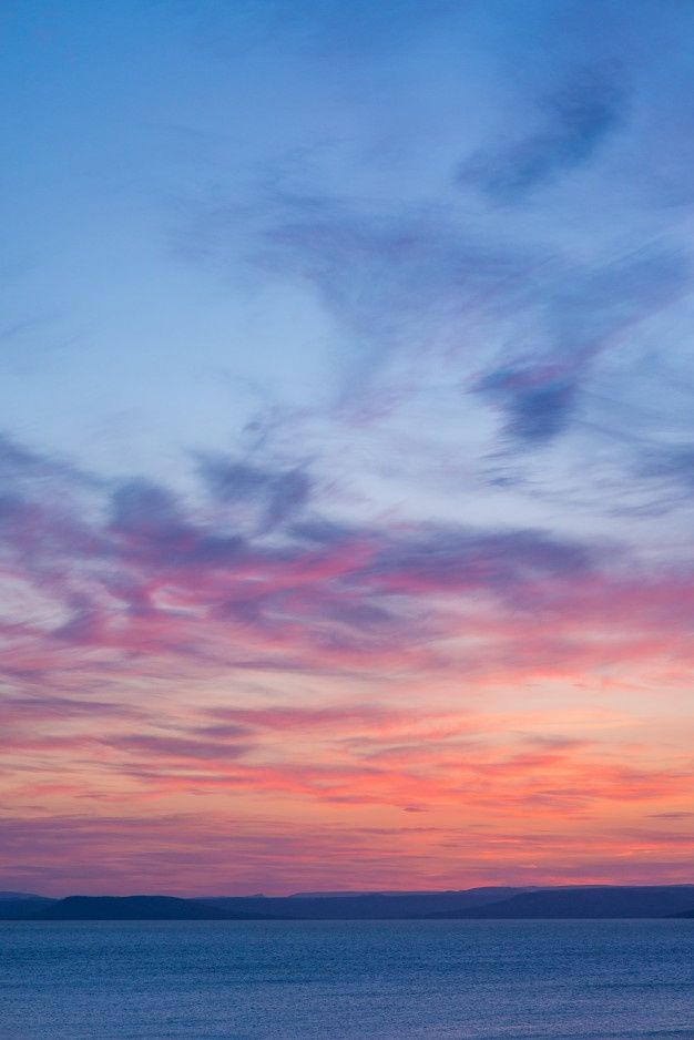 the sun is setting over the ocean with clouds