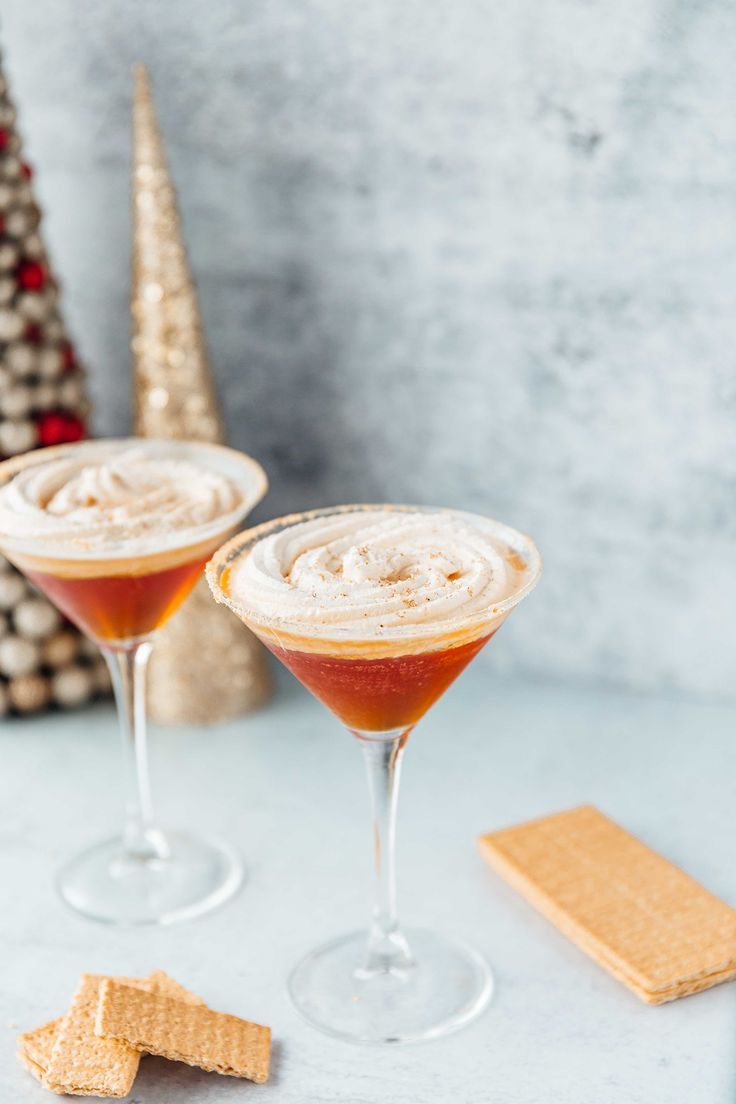 two glasses filled with drinks next to crackers