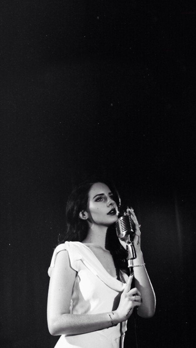 a black and white photo of a woman holding a microphone in front of her face