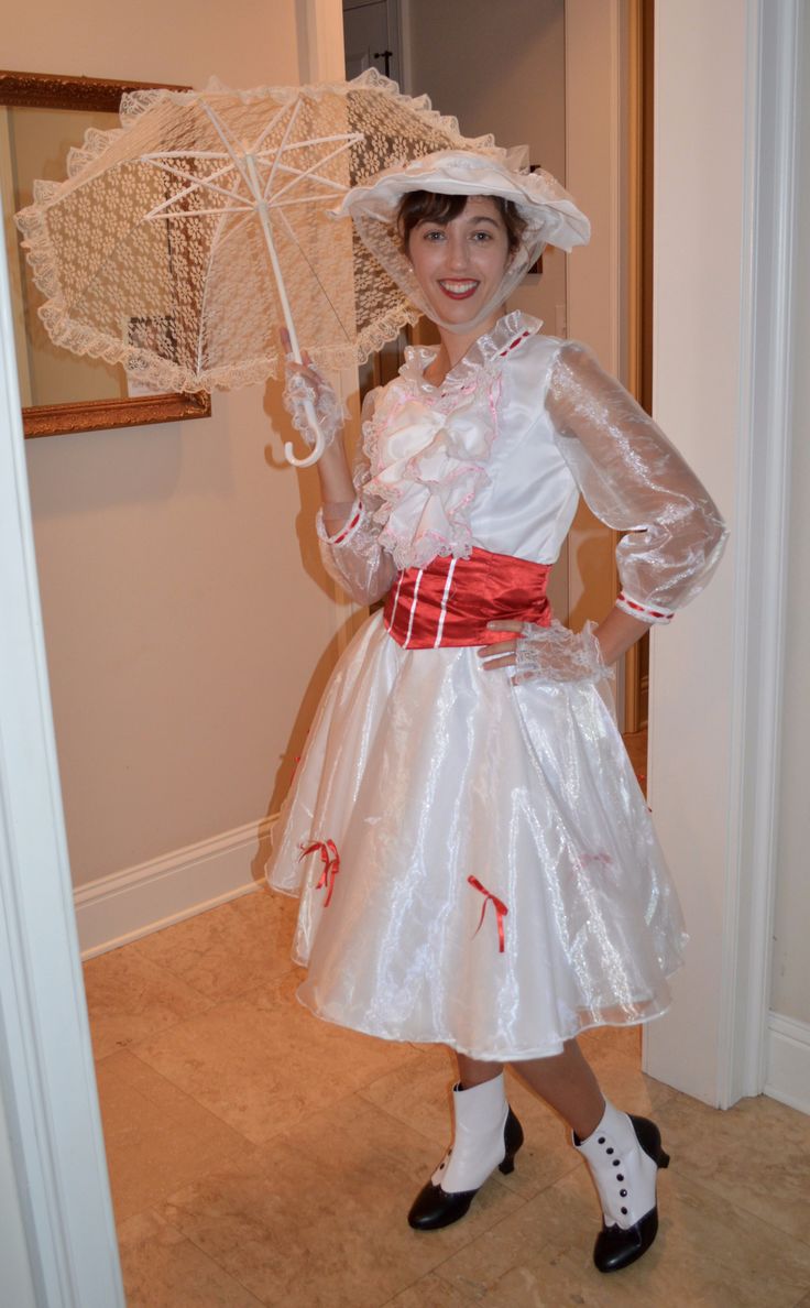 a woman in a white dress and hat holding an umbrella while posing for the camera