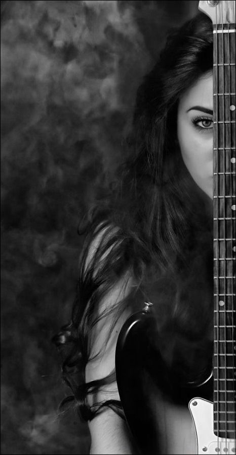 a woman with long hair holding a guitar in front of her face and looking at the camera