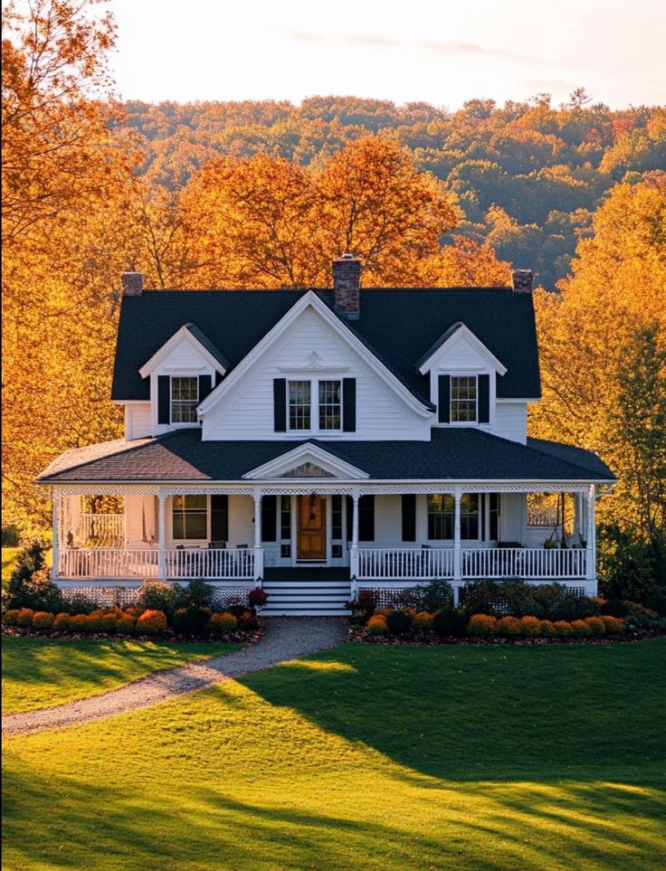 a large white house sitting in the middle of a lush green field next to trees