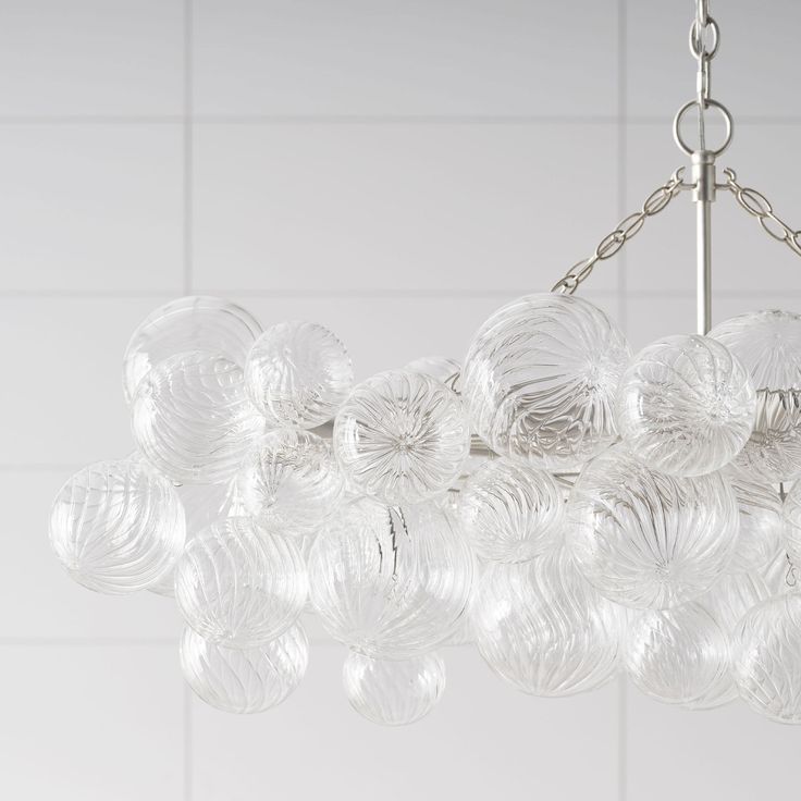 a chandelier made out of glass balls hanging from a chain on a tiled wall