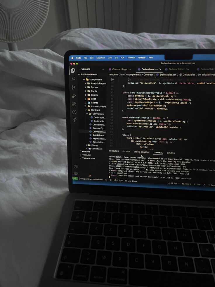 an open laptop computer sitting on top of a bed next to a white comforter