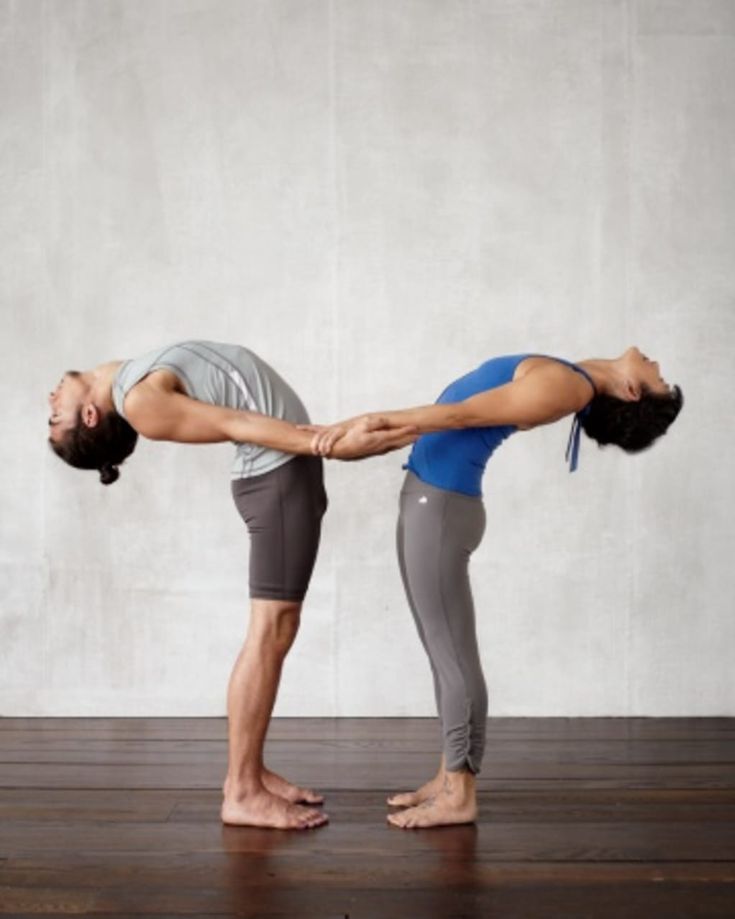 two people are doing yoga poses in front of a white wall and wood flooring