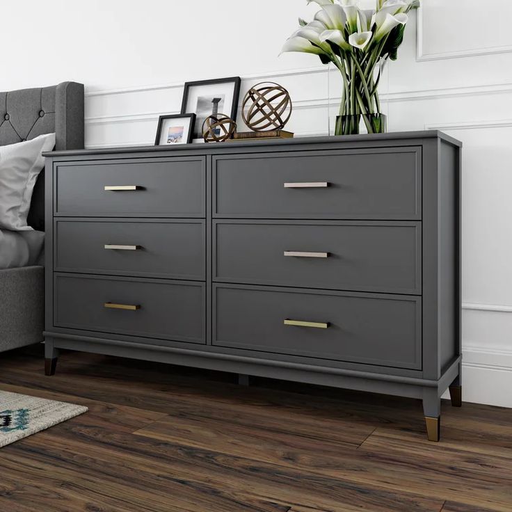 a bedroom with a gray dresser and white walls