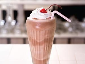 there is a chocolate milkshake with whipped cream and a cherry on the top