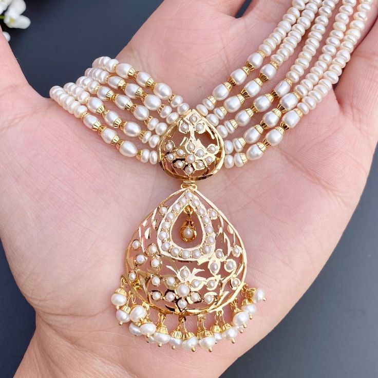 Featured is a fine mala pendant set or a short necklace in 22k gold set with freshwater pearls. The necklace can also be worn as a choker with tassle adjustment. The necklace weighs 33.25 gms including 0.86 gms in the hanging pearls and 21.5 gms of pearl in the mala The earrings weigh 9.76 gms including 0.96 gms in the hanging pearls. Gold Pendant With Pearl Mala, Traditional Gold Pearl Mala, Festive 22k Gold Pearl Pendant Jewelry, Elegant Handmade Gold Mala, Gold Bollywood Necklace With Pearl Pendant, 22k Gold Jewelry Necklaces, 22k Gold Jewelry, Pearl Necklace Set, Gold Jewelry Necklace