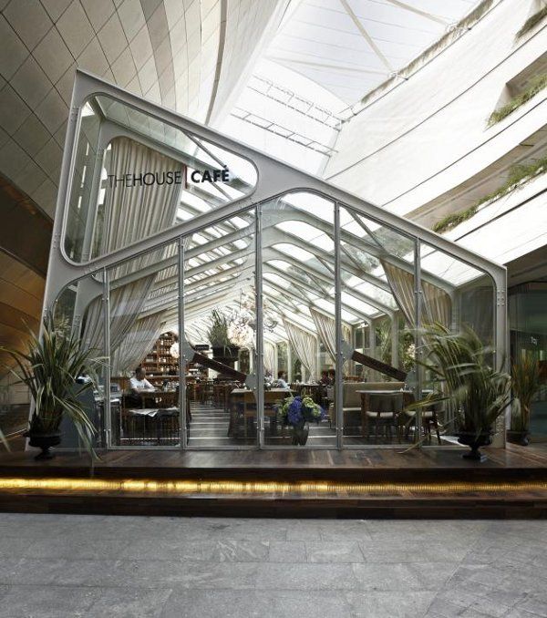 the inside of a building with glass walls and plants growing in it's center