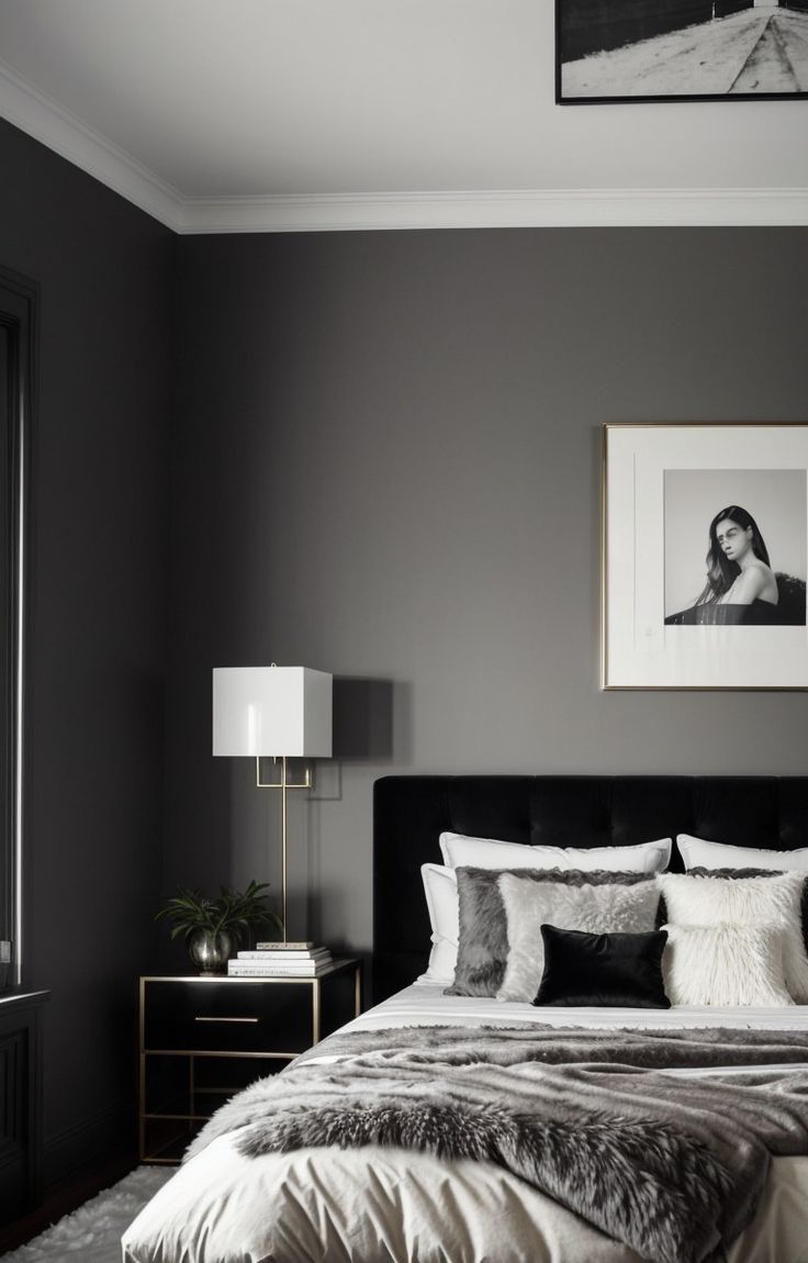 a bedroom with grey walls and white bedding, framed pictures on the wall above it