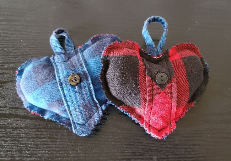 two pieces of cloth are sitting on a wooden surface, one is shaped like a heart and the other has a button