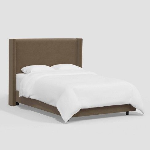 a bed with white sheets and brown headboard is shown in front of a gray background