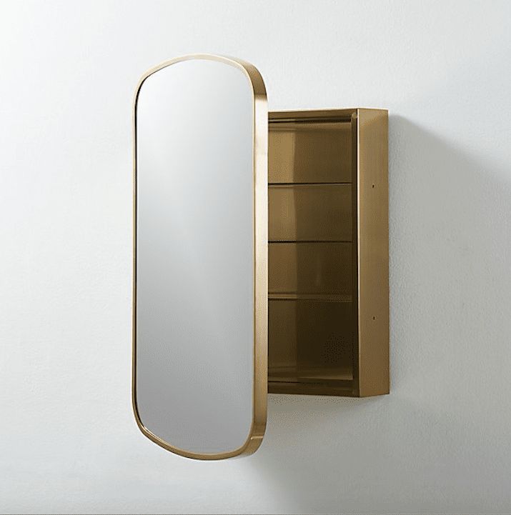 a mirror mounted to the side of a white wall next to a shelf with shelves