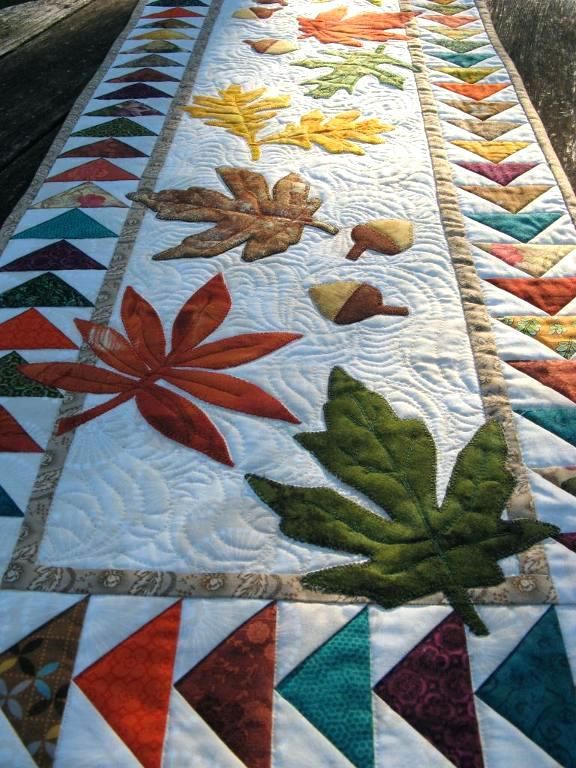 a quilted table runner with leaves on it