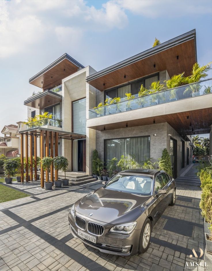 a car is parked in front of a house with large windows and balconies