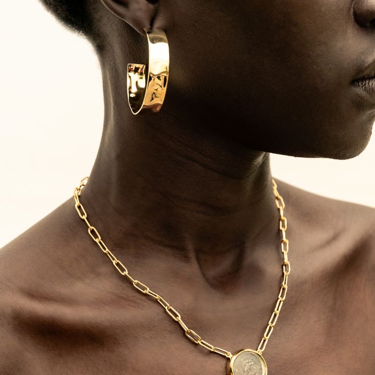 A fresh take on gold hoops: bold, yet sleek. The Maji Hoops are grounding and will have you feeling your most confident. With a handcrafted hammered effect, these earrings were responsibly made by our artisan partners in Kenya using traditional techniques in 24K gold-plated brass. Dimensions: Internal Diameter: 1.65in (42mm)Width of the hoop: 0.39in (10mm) Modern Gold Hammered Hoop Earrings, Hammered Gold-plated Small Hoop Earrings, Modern Hammered Jewelry In Recycled Gold, Small Gold Plated Hammered Hoop Earrings, Small Hammered Gold-plated Hoop Earrings, Yellow Gold Hammered Metal Hoop Earrings, Tarnish-resistant Recycled Gold Hoop Earrings, Modern 14k Gold Hammered Hoop Earrings, Hammered Gold-plated Hoop Jewelry