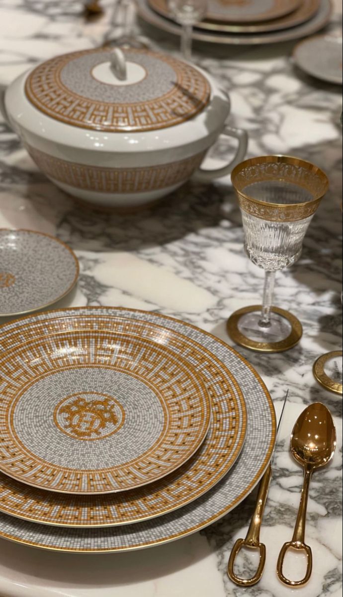 the table is set with gold and white plates, utensils, and silverware