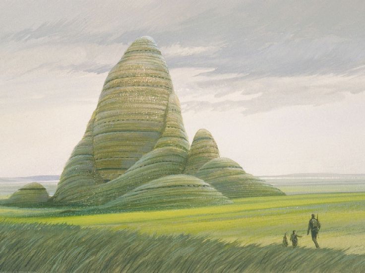 two people are standing in the grass near some large mounds that look like they have been made out of straw