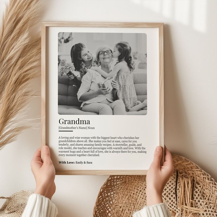 a person holding up a framed photo in front of a wall with an article about grandma on it