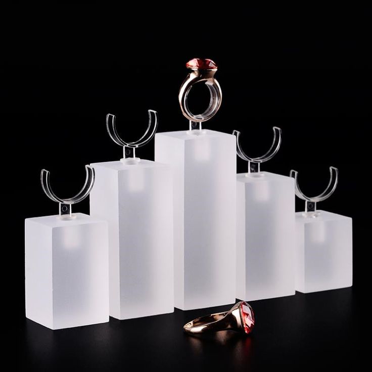 three rings are sitting on top of white cubes and one has a red ring in the middle