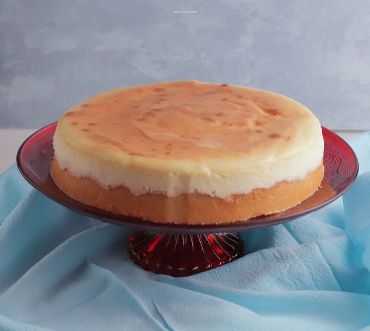 a cake sitting on top of a red plate next to a blue cloth covered table