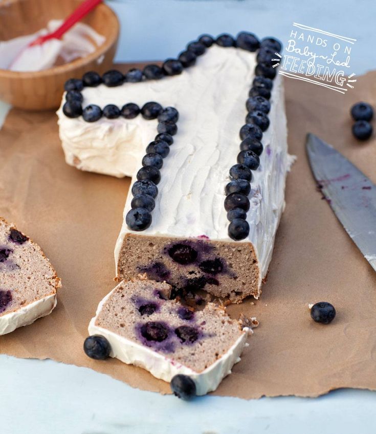 a cake with blueberries and cream frosting sitting on top of a piece of paper