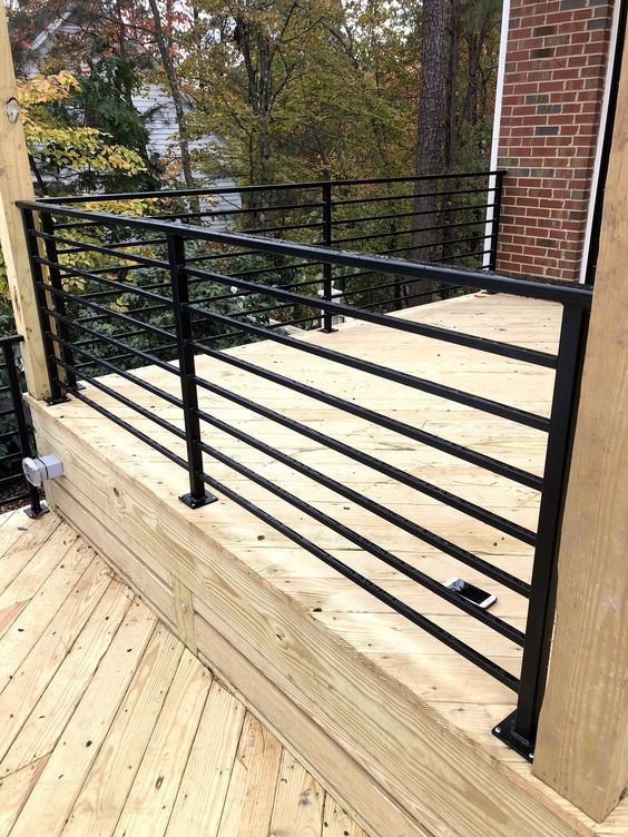 a wooden deck with black iron railings