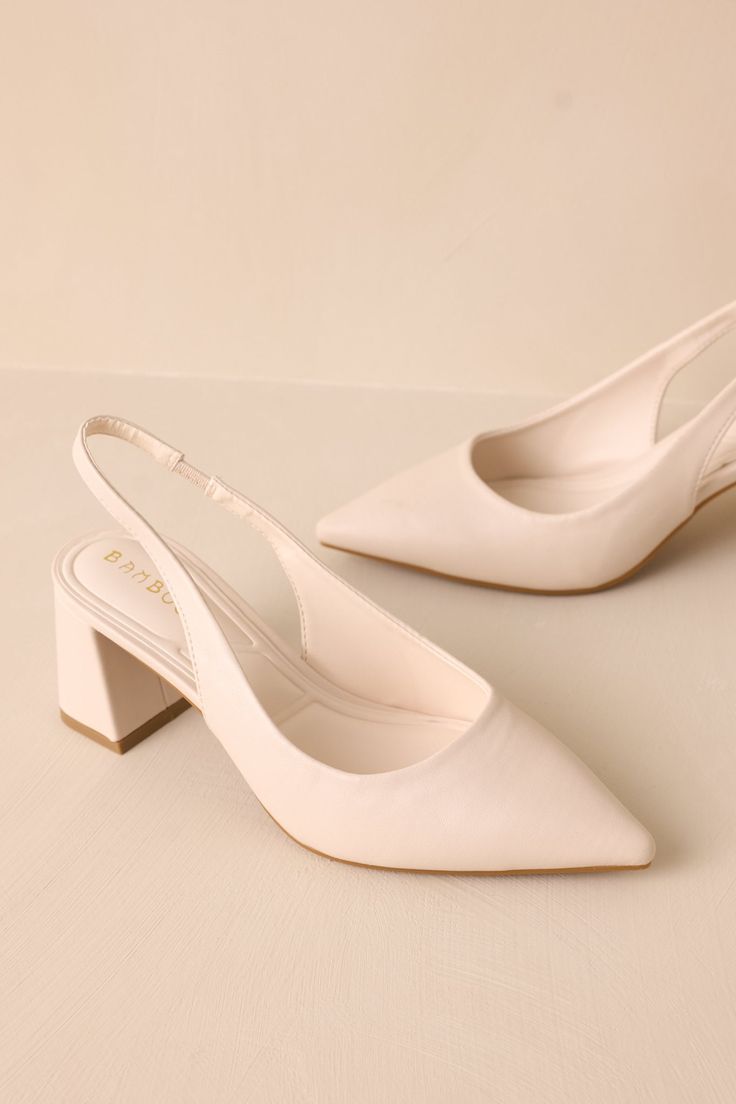 a pair of white high heeled shoes sitting on top of a table