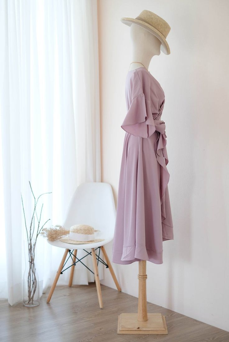 a mannequin wearing a purple dress and hat in front of a white chair