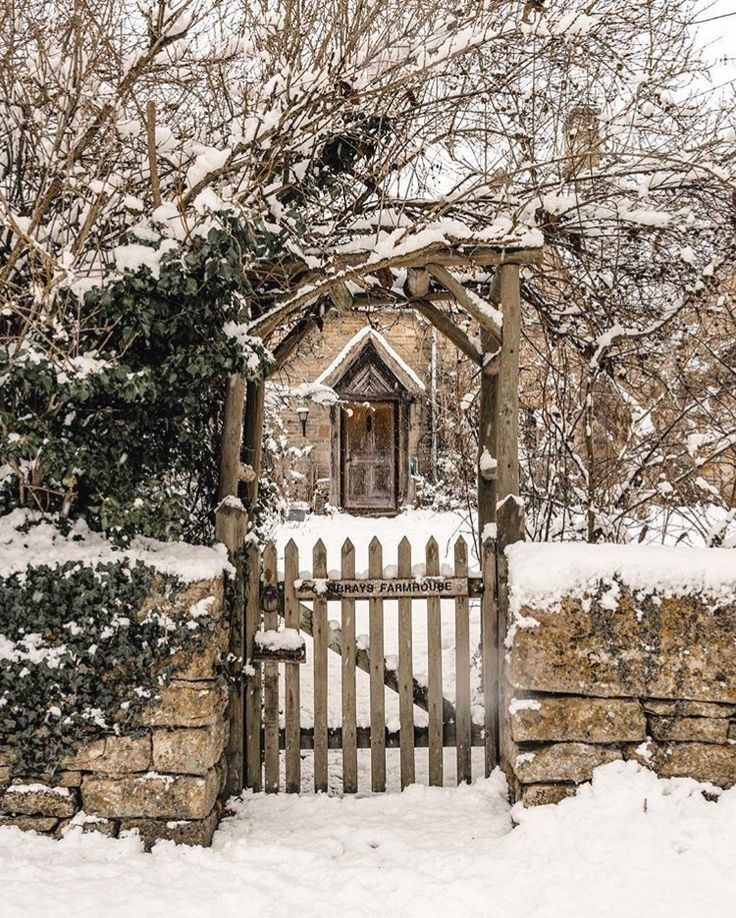 an old stone building with a wooden gate in the snow