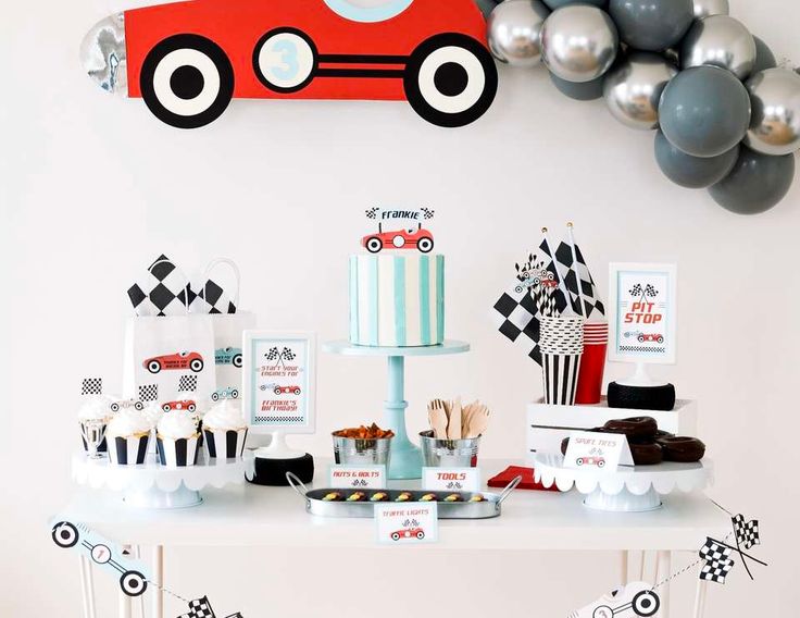 a table topped with cakes and desserts next to balloons